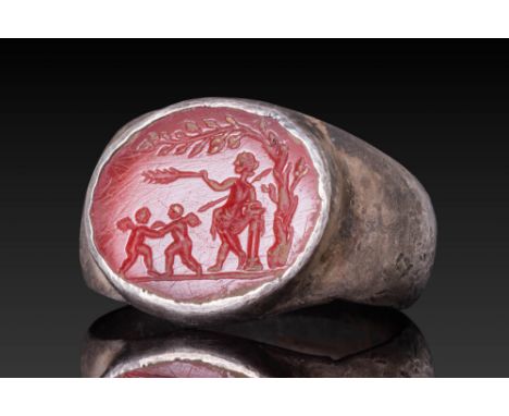 Ca. AD 1 - 200.A carnelian intaglio engraved with a mythological scene, showing a central draped figure holding a palm branch