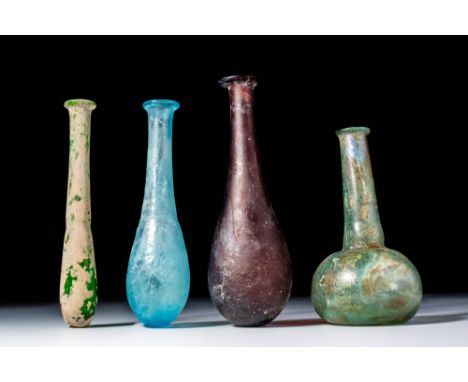 Ca. AD 1 - 300. A collection of four glass unguentaria. The first on the left has a narrow neck and an elongated body in gree