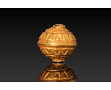 Ca. 350 - 300 BC. A gold biconical bead with a circular perforation running through its axis. The body is decorated with a pa