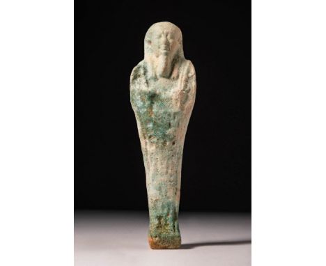 Late Period, 26th Dynasty, Ca. 550 BC. A pale blue glazed faience ushabti with arms crossed over the chest, holding a pick an