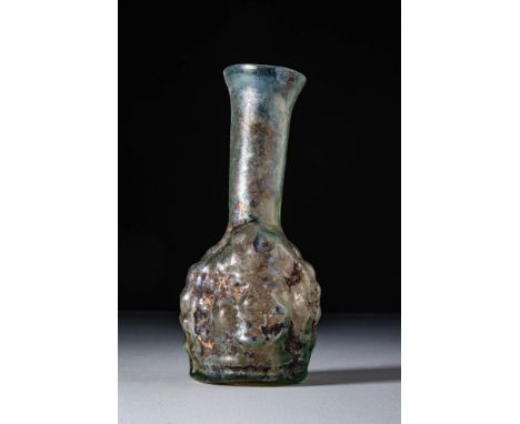 Ca. AD 300 - 400.A pale green glass unguentarium with a mould-blown body in the form of a head, transitioning into a long cyl