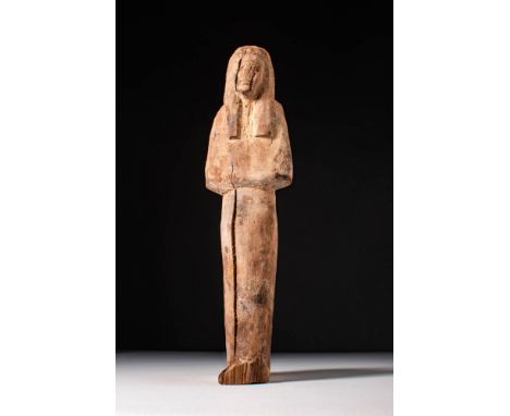 New Kingdom, Ca. 1550 - 1069 BC. A wooden ushabti figure depicted standing with hands placed on the chest and wearing a tripa