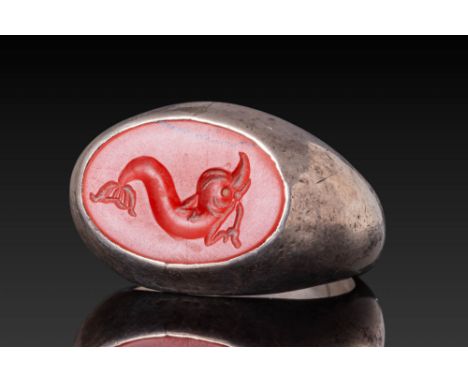 Ca. 100 BC - AD 100.A red jasper intaglio engraved with a stylised dolphin depicted with an arched body, raised head, and pro