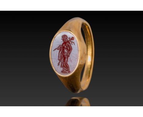 Ca. AD 1 - 300 . A gold ring set with an oval red stone intaglio engraved with a standing male figure of Asclepius holding a 