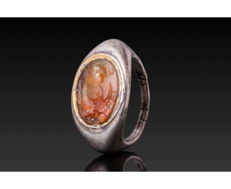 Ca. AD 50 - 200.An oval carnelian intaglio engraved with a central depiction of an eagle with raised wings, flanked by milita