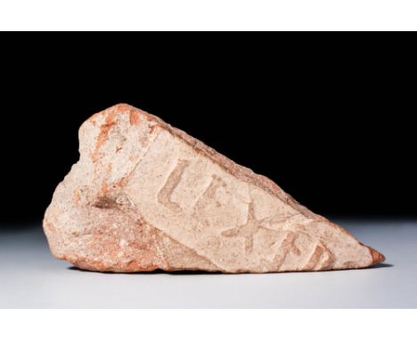 Ca. AD 1 - 400. A triangular fragment of a brick bearing a partial legionary stamp. The surface is light reddish with worn, i