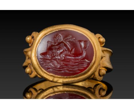 Ca. AD 100-300. An oval carnelian intaglio engraved with a depiction of Eros riding a dolphin showing the nude figure seated 