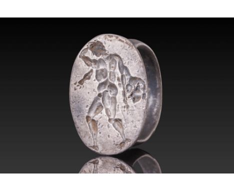 Ca. 400 BC. A silver ring with a flat-section hoop and an oval bezel engraved with a muscular nude figure of Heracles stridin