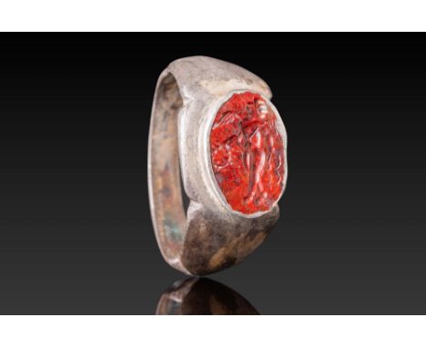 Ca. AD 300. A Roman red stone intaglio depicting a standing Victory with spread wings, holding a wreath in her right hand and