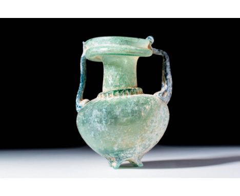 Ca. AD 300 - 500.A translucent pale green glass amphoriskos with a globular body tapering to a pointed base with four rounded