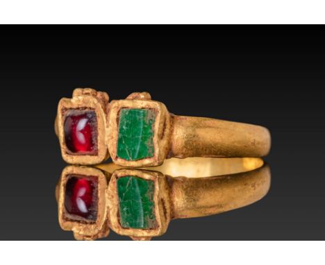 Ca. AD 300 - 500.A gold ring set with a rectangular garnet cabochon and a flat-cut emerald in adjacent box-shaped settings at