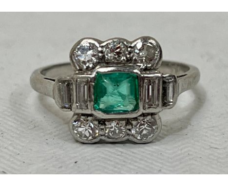 A 1940s platinum ring set with an emerald flanked by four baguette cut diamonds and six old cut diamonds. 3g gross, size K½.