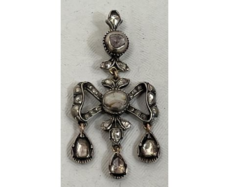 An 18th Century 'candlelight' cut diamond bow shaped corsage pendant in silver with three stones en-trembleuse. 58mm high.