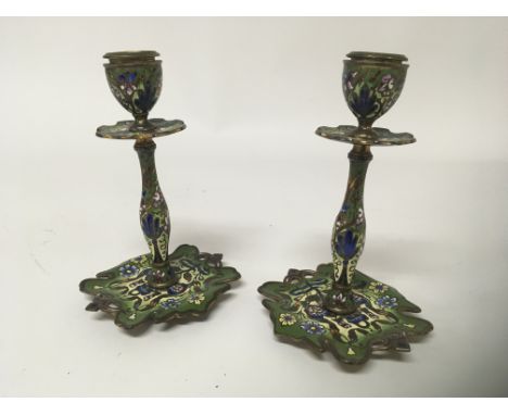 A pair of early 20th century enamel candle sticks with shaped bases. decorated with flowers and foliage. Hight 15cm
