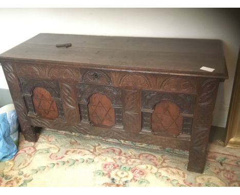 An 18th century oak trunk with a hinged top above panels inlaid with a star pattern.