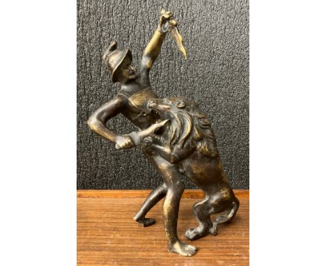 A bronze figure of a gladiator fighting a lion 
