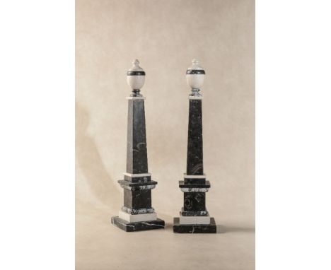 A pair of black fossil marble and white marble models of obelisks, 20th century, each with an urn finial, the tapering shafts