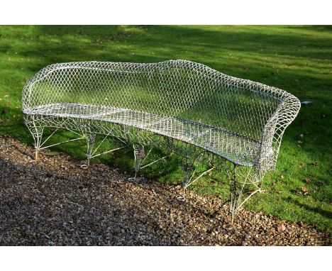 A painted wrought iron and wirework exedra bench, early 20th century, with curved frame and 'camel back', on five scrolled an