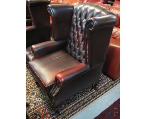 20th Century leather button back wing chair on cabriole legs together with a matching button back footstool. (2)