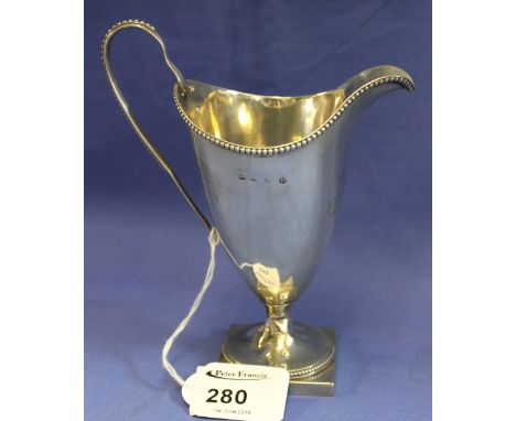 Silver helmet shaped cream jug with engraved initials raised on square base.