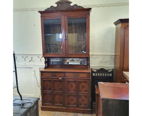 A walnut bookcase on cupboard, having a pair of bar glazed doors above two frieze drawers with a pair of carved doors below, 