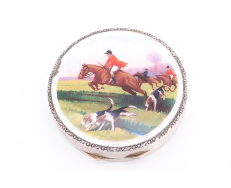 A 1920s enamelled silver patch box, of circular form, the top enamelled with a hunt scene, having a gilt interior with a mirr