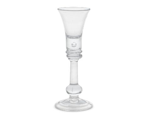 A baluster cordial glass, circa 1725-30The flared trumpet bowl with a deep solid base enclosing a tear, on a collar above a d