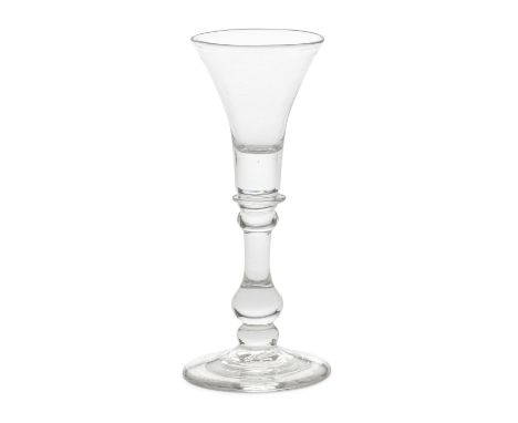 A good baluster wine or cordial glass, circa 1725-30The flared trumpet bowl with a deep solid base enclosing a tiny air bead,