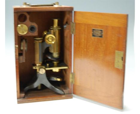 An early 20th century brass students microscope, stamped Baker, 244 High Holborn, London, in fitted mahogany case, also beari