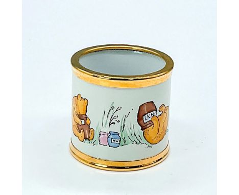 Hand painted napkin ring featuring the popular storybook character Winnie the Pooh with his head stuck in a jar. Gold rimmed 