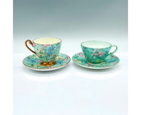 A set of 2 green cups and saucers adorned wildflowers pattern. One (13382) with gilded trims, and the other (13453) with gree