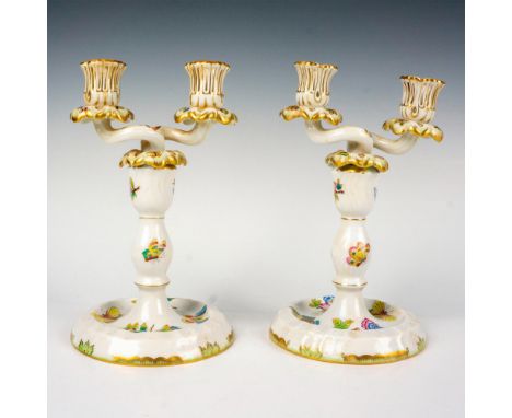 Hand-painted porcelain double candlestick holders with open work capitals, intertwined arms, and leaf-shaped drip pans. The d