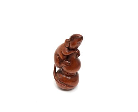 A carved Chinese hardwood netsuke - Rat holding a bag of grain