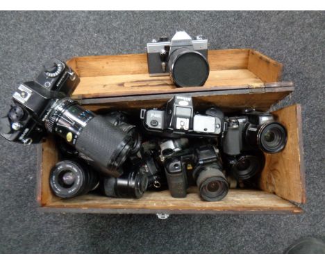 A wooden storage box containing various cameras and lenses including Praktica, Canon, Minolta etc 