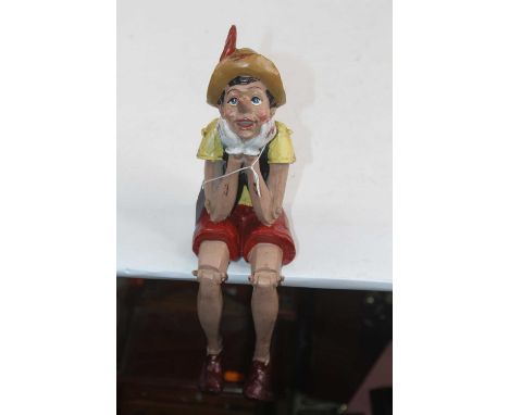 A painted resin model of Pinocchio, shown seated, height 28cm