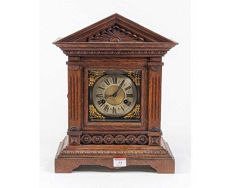An early 20th century oak cased mantel clock of architectural form, the silvered chapter ring with Roman numeral markers and 