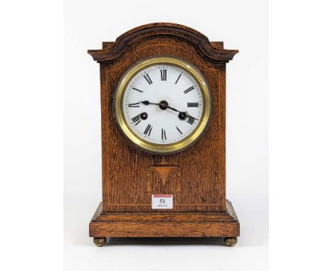 A late Victorian oak cased mantel clock, the enamel dial with Roman numeral markers and twin winding holes for an eight day m