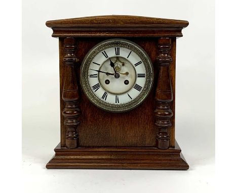 An early 20th century oak cased mantel clock, the enamel chapter ring showing Roman numerals, having visible anchor escapemen