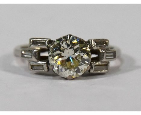 An Art Deco diamond ring, the central circular diamond with three baguette cut collet set diamonds on each side, platinum set