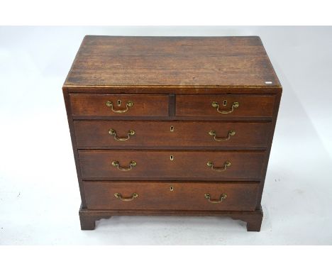A George III oak caddy top chest ofm two short over three long graduated drawers, with brass swan-neck fittings, raised on sh