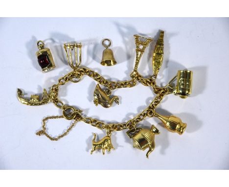 A 9ct yellow gold curb bracelet with nine various mainly 9ct charms attached including Eiffel Tower, fish, bird cage, teapot,