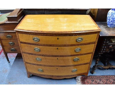 A George III bowfront cross-banded satinwood chest of four long graduated drawers, with brass oval fittings, raised on splaye