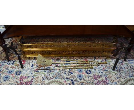 An antique pierced brass fender on paw feet to/w a trio of brass fire tools and a pair of steel fire dogs (lot), 121 cm wide,