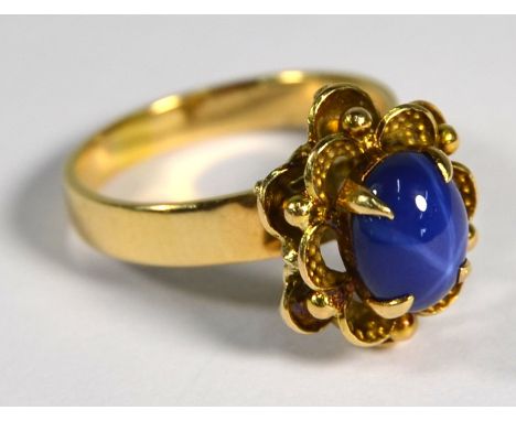 A star sapphire ring, the oval blue cabochon sapphire with star radiating off-centre, in yellow metal high scroll and claw se