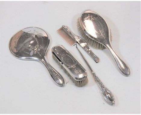 An early 20th century silver backed dressing table set, comprising two brushes, a comb, a mirror, and a button-hook, decorate