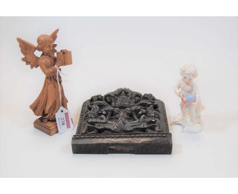 A small carved oak panel, depicting a central figure with two monkeys at his feet; together with a Goebel figure of a churub;