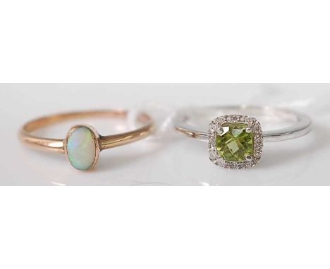 A 9ct white gold, peridot and diamond cluster ring, featuring a cushion cut peridot within a border of 12 round brilliant cut