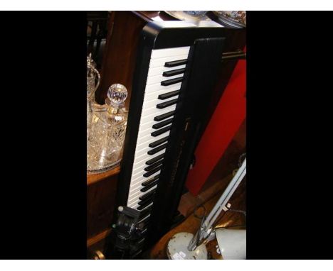 A Casio CPS-7 electronic keyboard and stand together with a tripod for camera