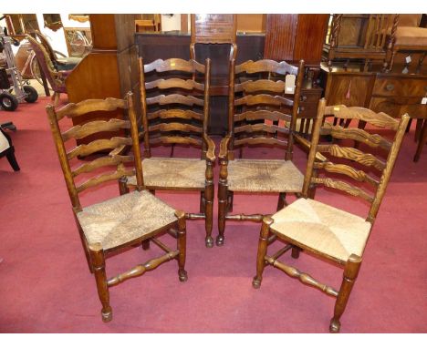 A set of four elm and fruitwood ladder back rush seat dining chairs (2+2)