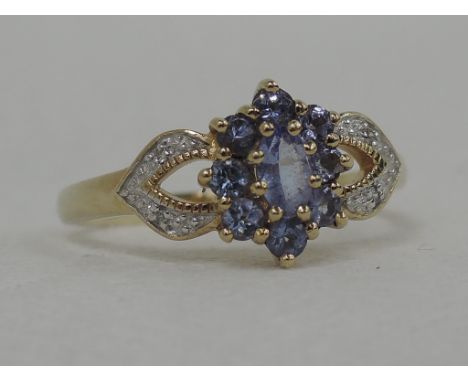 A lady's dress ring having an oval tanzanite cluster to diamond chip set open shoulders on a 9ct gold loop,  size R
